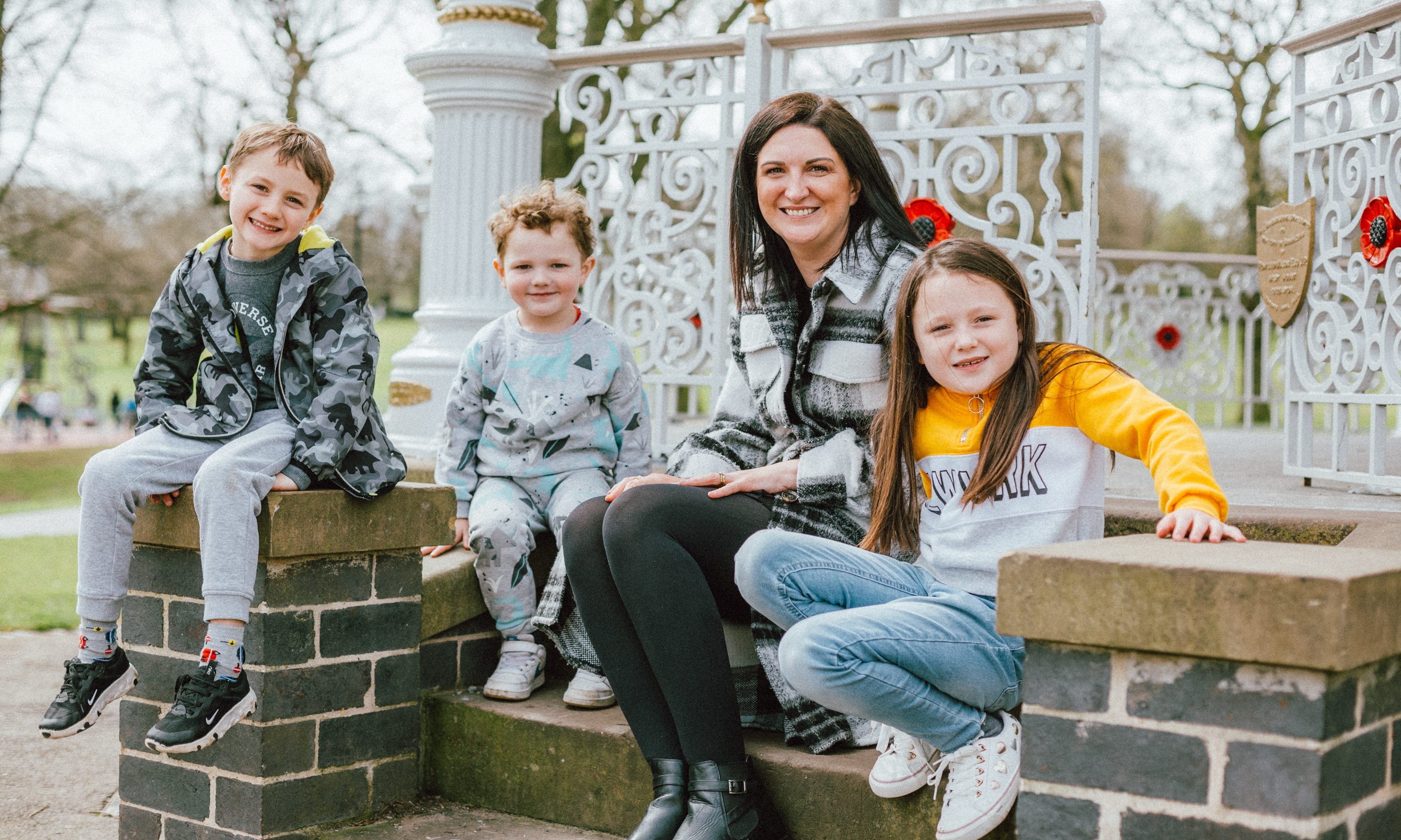 A Woman And Three Children Sitting On Some Steps Outside